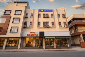 A multi-story hotel with a modern facade, air conditioning units, and a visible restaurant on the ground floor. - Fabhotel Le Sancy (New Delhi)