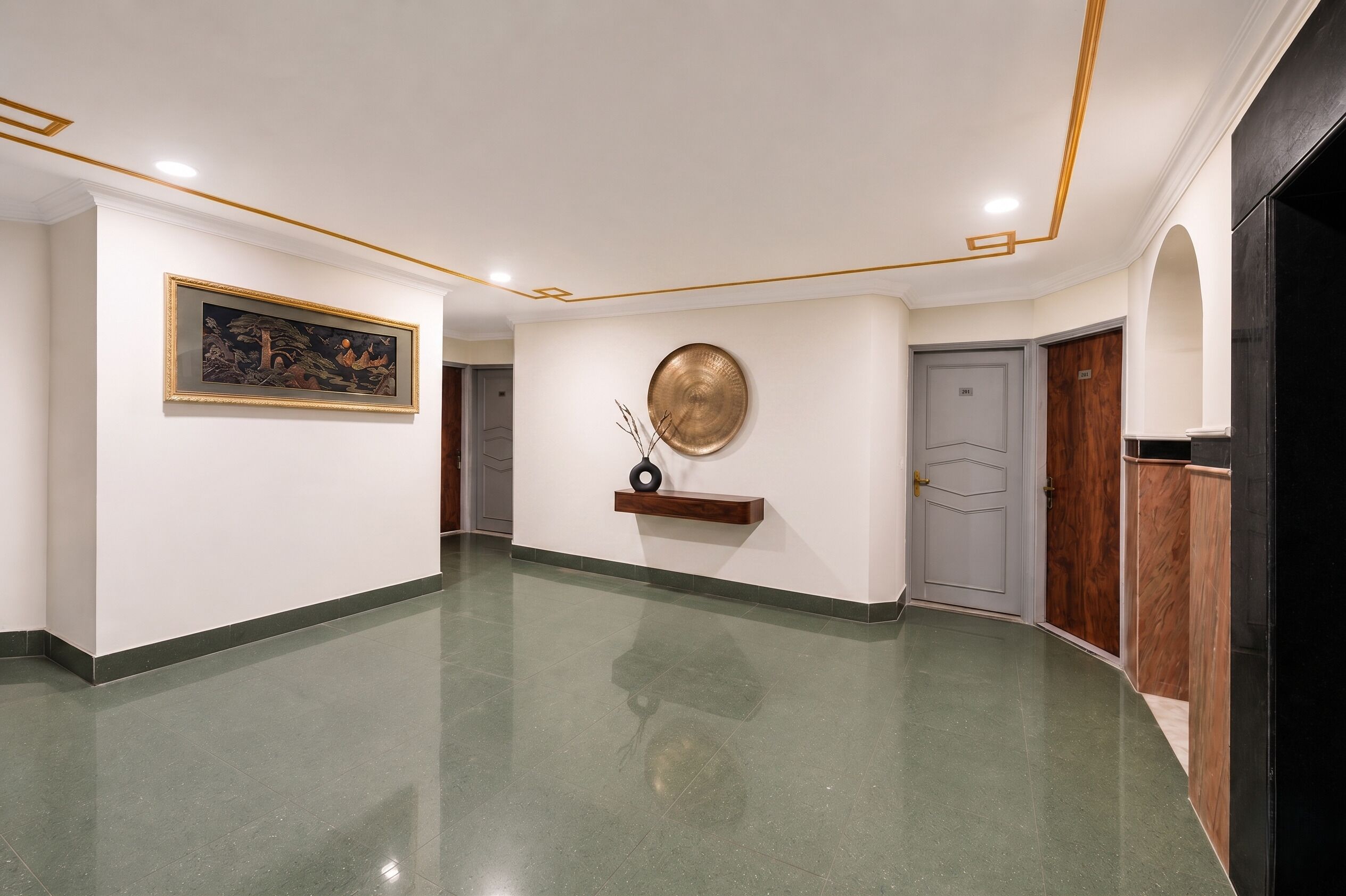 A hallway with a polished floor, a framed painting, a decorative plate, and a door.