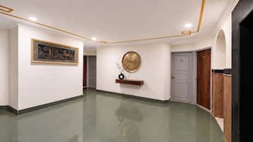 A hallway with a polished floor, a framed painting, a decorative plate, and a door.