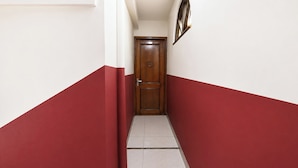 Un passadís estret amb una porta de fusta al final, parets blanques i parets pintades de vermell.