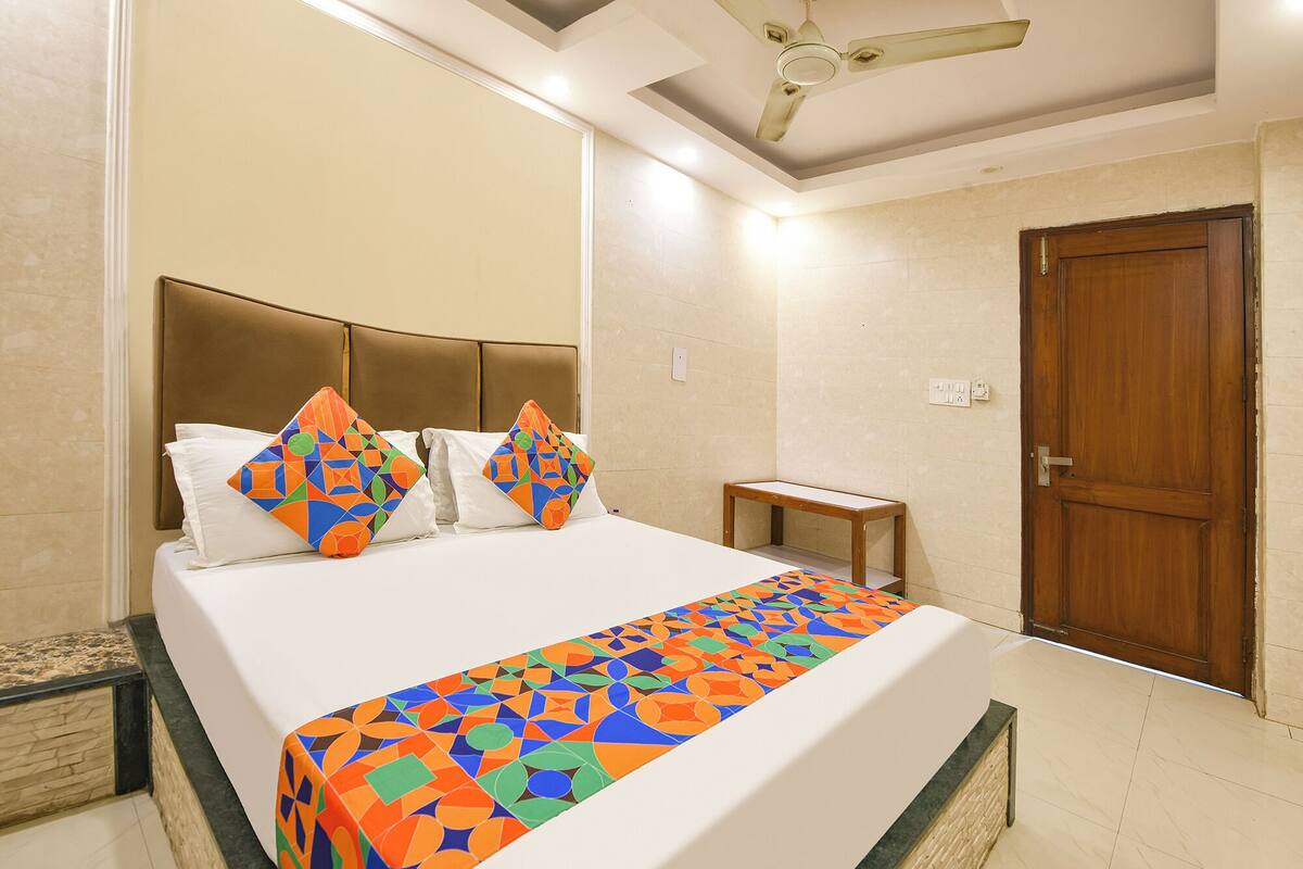 Una habitación de hotel con una cama, una puerta de madera, un ventilador de techo y una mesita.