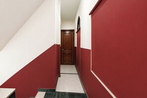 Unes escales estretes amb parets vermelles i blanques, una porta de fusta al final i un sòl de rajola.