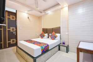 A bedroom with a bed, pillows, a bedside table, a nightstand, a ceiling fan, and a door.