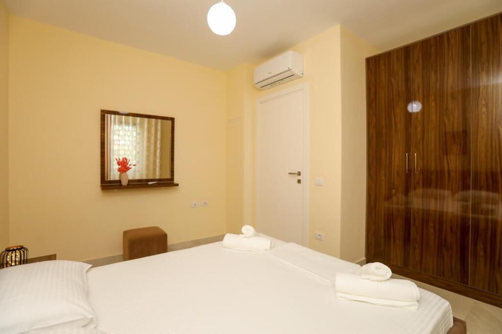 A hotel room with a bed, a mirror, a wardrobe, and an air conditioning unit.