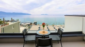 A balcony with a table and chairs, overlooking a beach and the sea. - Velaris Apartments (Vlore)