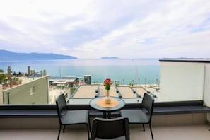 A balcony with a table and chairs, overlooking a beach and the sea. - Velaris Apartments (Vlore)