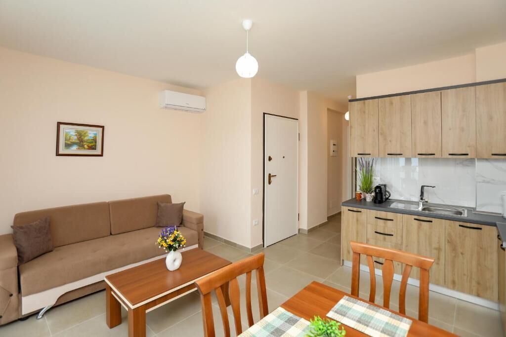 Un espacio habitable compacto con sofá, mesa de comedor, sillas, kitchenette y una puerta.