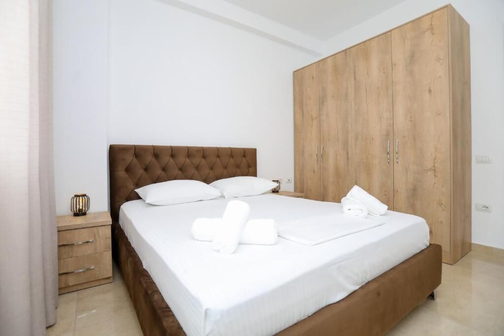 A bedroom with a bed, a wooden wardrobe, a nightstand, and a small table with a decorative item.