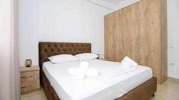 A bedroom with a bed, a wooden wardrobe, a nightstand, and a small table with a decorative item.