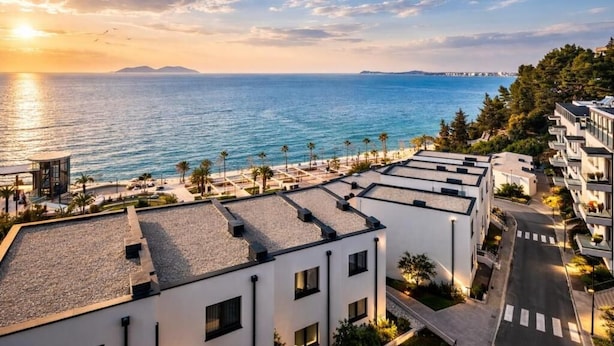 A coastal hotel with a rooftop terrace, a view of the sea, and a promenade with palm trees. - Velaris Apartments (Vlore)