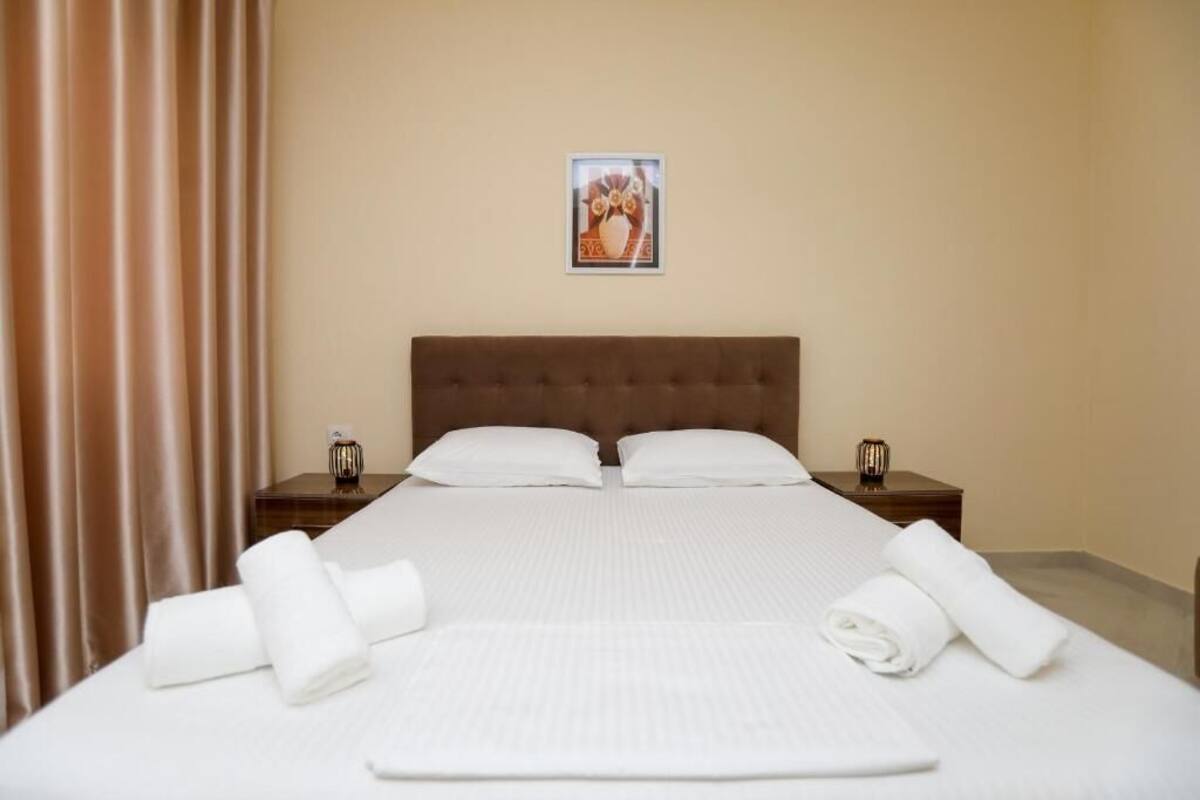 Una habitación de hotel con una cama grande, dos mesitas de noche y un cuadro enmarcado en la pared.