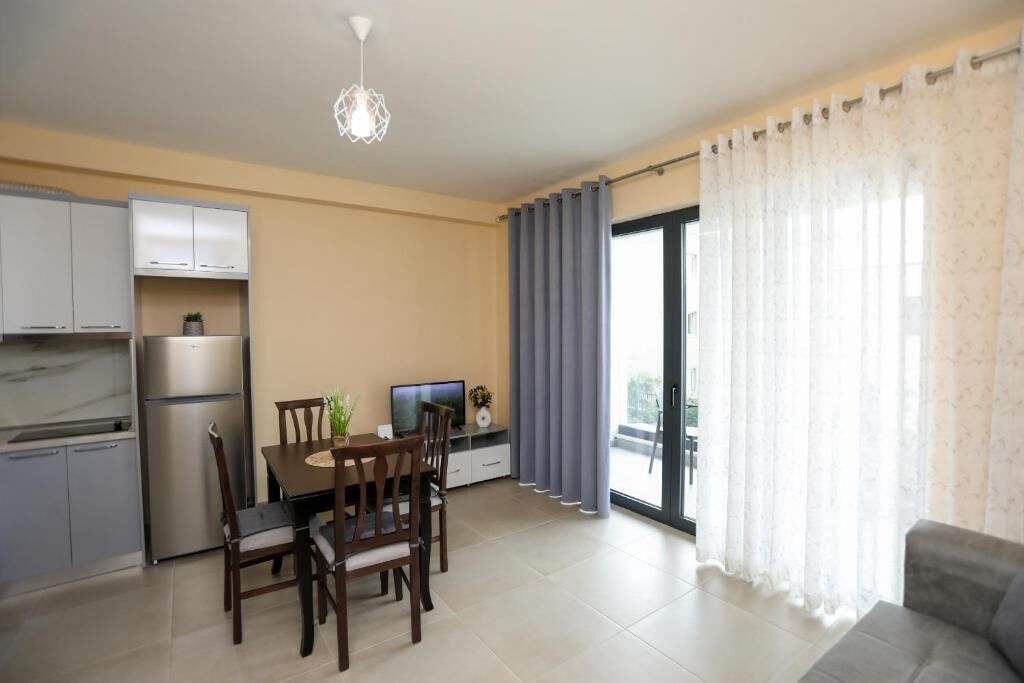 Eine moderne Wohnung mit Essbereich, Küche und einem Balkon mit Vorhängen.