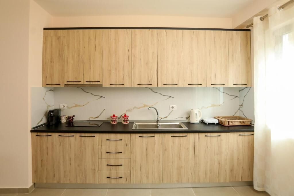 Eine Küche mit Holzschränken, einer schwarzen Arbeitsplatte und einer Marmor-Spritzschutzwand.