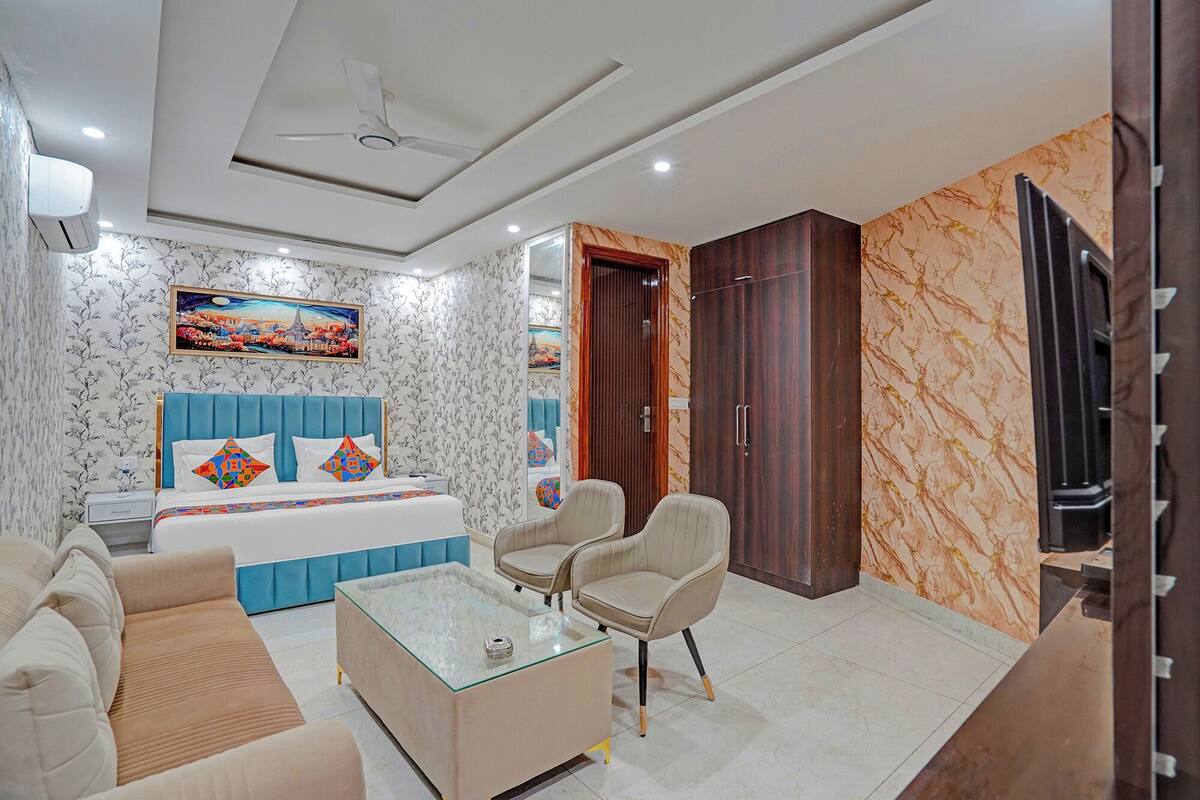 Una habitación de hotel con cama, sofá, mesa de centro, televisor y armario.