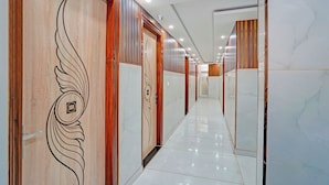 Un pasillo con paneles de madera, suelos de mármol blanco y varias puertas.