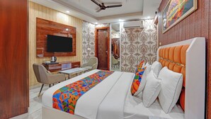 Una habitación de hotel con cama, escritorio, silla, televisor y ventilador de techo.