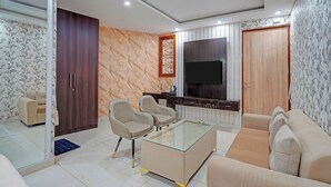 Una sala moderna con una mesa de centro de vidrio, dos sillones, un sofá, un televisor y un armario de madera.