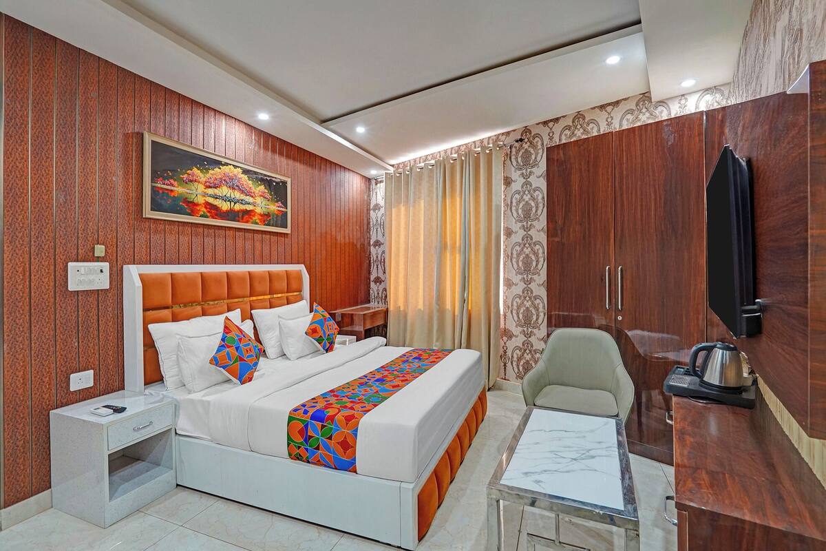 Habitación de hotel con cama, mesita de noche, silla, escritorio y televisión.