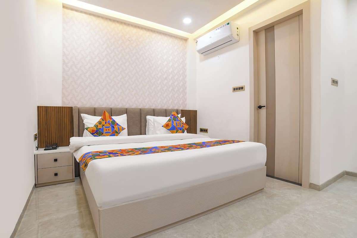 Un dormitorio moderno con cama, mesitas de noche, un equipo de aire acondicionado y una puerta.