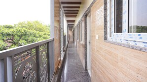 A narrow corridor with a balcony on one side, a wooden wall on the other, and a window with insulation. - FabHotel MR Guest Line - Banashankari (Bangalore)
