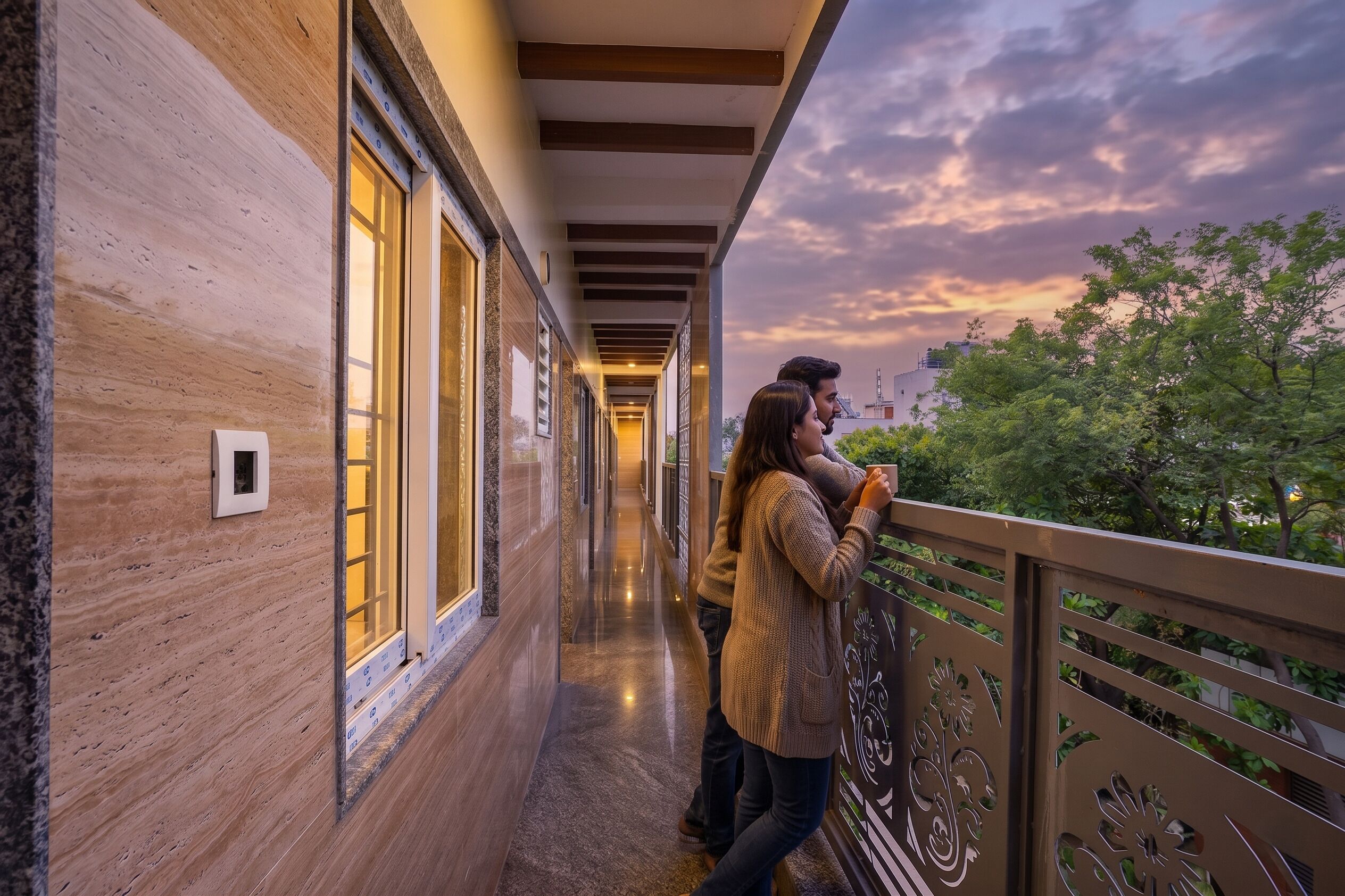 A corridor with wooden walls and large windows, leading to a balcony with decorative railings.