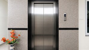 Un ascensor con una puerta metálica, un panel digital que muestra el número 4 y una pared con textura.