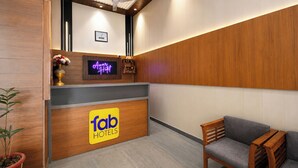 A hotel reception area with a wooden reception desk, a neon sign, a clock, and a seating area. - Fabhotel Amar Residency (New Delhi)