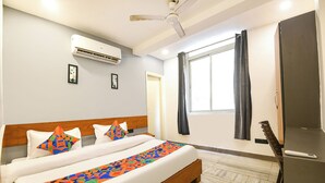 A hotel room with a bed, an air conditioner, a ceiling fan, a window with curtains, and a door. - Fabhotel Amar Residency (New Delhi)