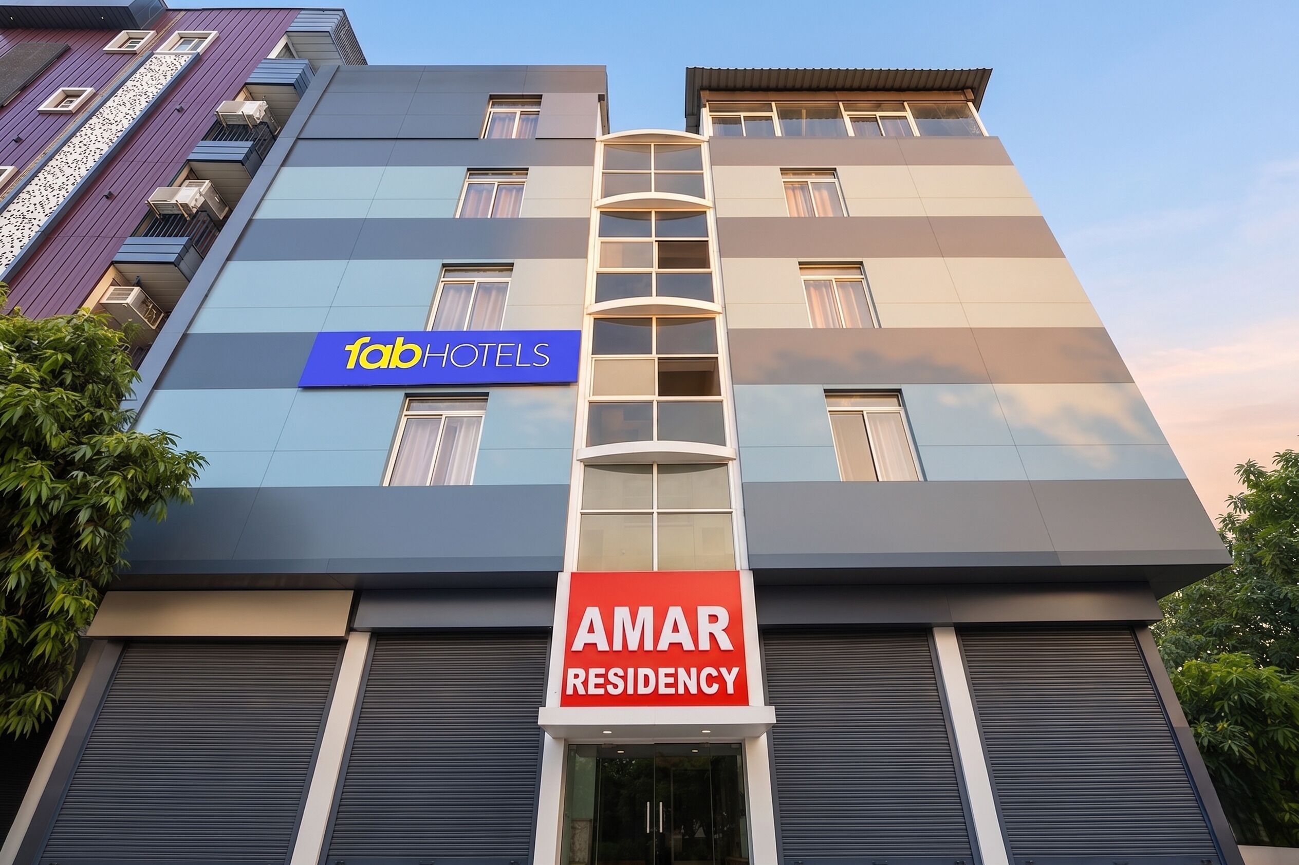 A multi-story building with a sign for 'Fab Hotels' and 'Amar Residency.'