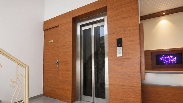 A hotel reception area with a reception desk, a neon sign, and an elevator. - Fabhotel Amar Residency (New Delhi)