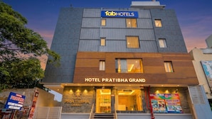 Um edifício de hotel moderno com uma placa indicando 'Hotel Pratibha Grand' e 'Tab Hotels'.