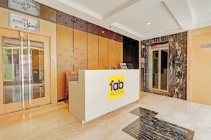 A hotel reception area with a modern design, including a reception desk, a glass door entrance, and a marble floor. - FabHotel Pratibha Grand - near Vijayawada Junction (Vijayawada)
