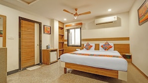 Quarto de hotel com cama, ventoinha no teto, ar condicionado, janela e porta.