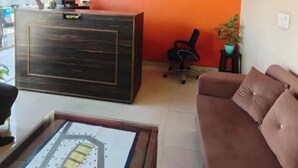A reception desk, a brown sofa, a ceiling fan, and a framed artwork on the wall. - Fabhotel Radhy Stay (Jaipur)