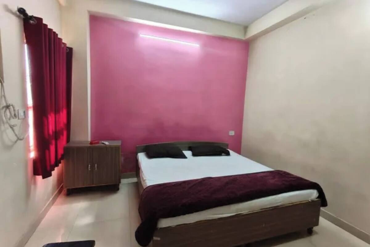 Ein Schlafzimmer mit Bett, Nachttisch, Kleiderschrank und einem roten Vorhang.