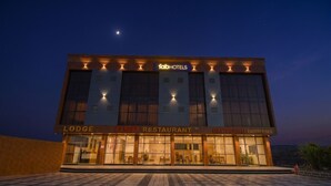 Um edifício com uma placa que diz 'fabHOTELS' e 'Lodge' no andar térreo, e 'DSP RESTAURANT' e 'DAITAGURU ENTERPRISES' no andar superior.
