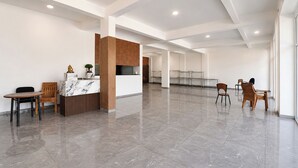 Um hall amplo com balcão de recepção, área de estar e um amplo espaço aberto.