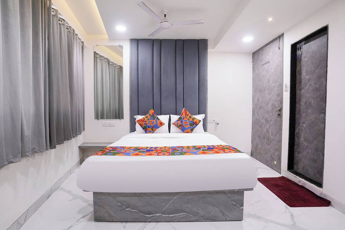 A modern bedroom with a large bed, grey curtains, a ceiling fan, and a marble floor.