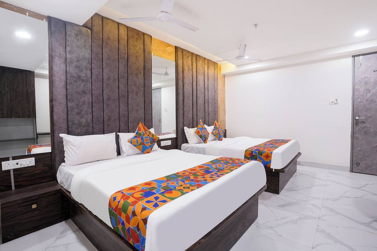 A hotel room with two beds, a wooden headboard, a mirror, a wardrobe, and a marble floor.