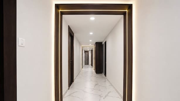 Un corridoio con pavimento in marmo, porte in legno e illuminazione a incasso.