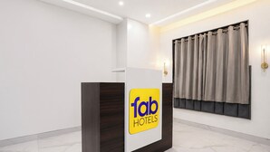 Una reception con un cartello che indica 'fab hotels', una finestra con tende e un pavimento in marmo.