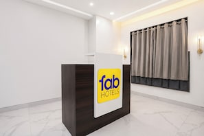 Una recepción con un cartel que dice 'fab hotels', una ventana con cortinas y un suelo de baldosas de mármol.