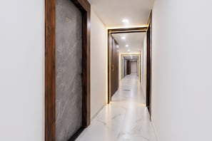 Un pasillo con suelo de mármol, marcos de puerta de madera y un letrero con un número en la pared.