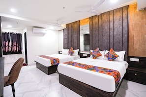 Habitación de hotel con dos camas, un espejo grande, una silla y un ventilador de techo.