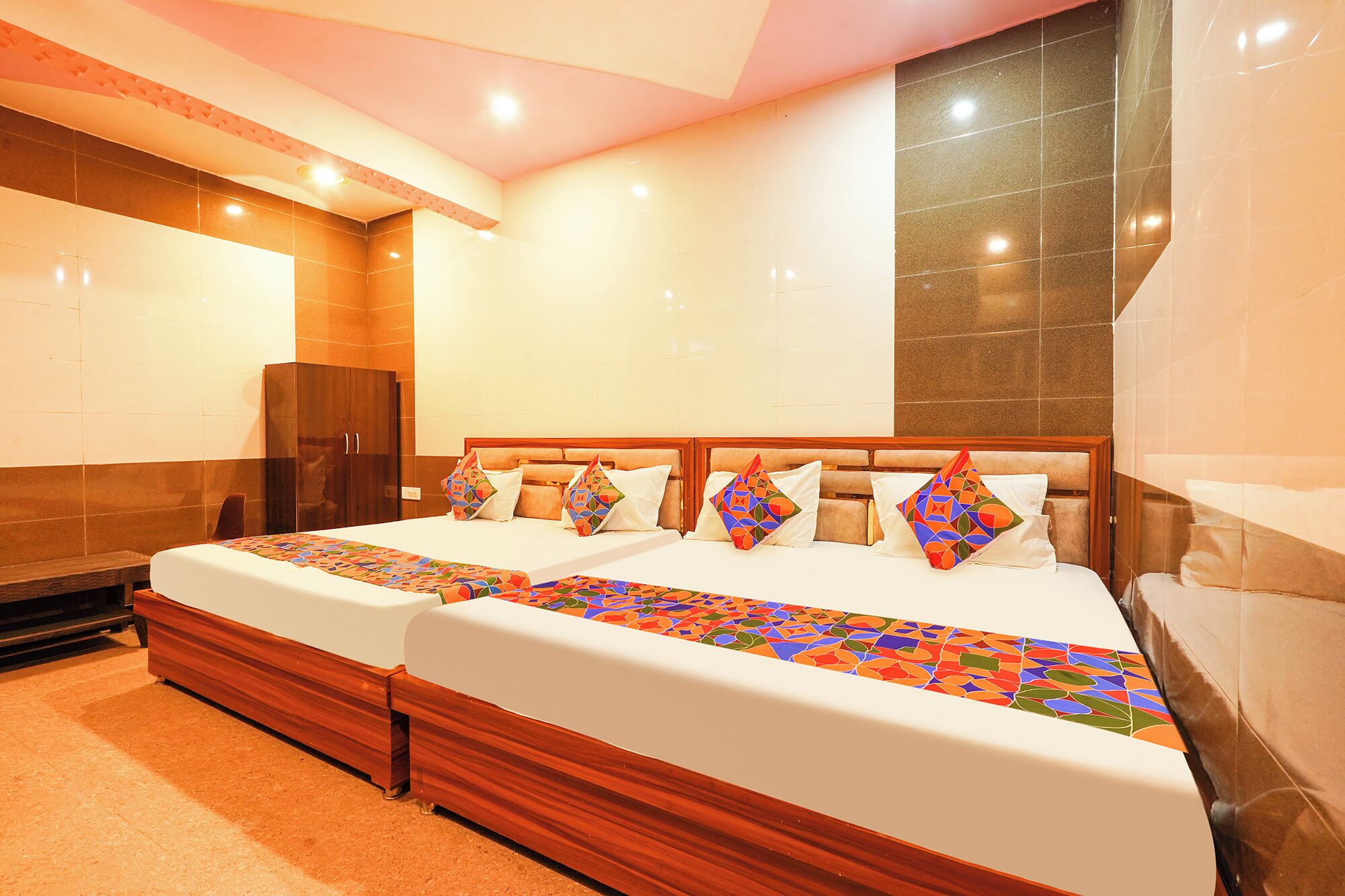 A hotel room with two beds, a wooden headboard, a large mirror, and a tiled wall.