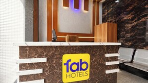 Ein Hotelrezeptionsschalter mit Marmorplatte, eine Sitzecke mit einer Bank und ein Schalter mit dem Schild 'fab hotels'.