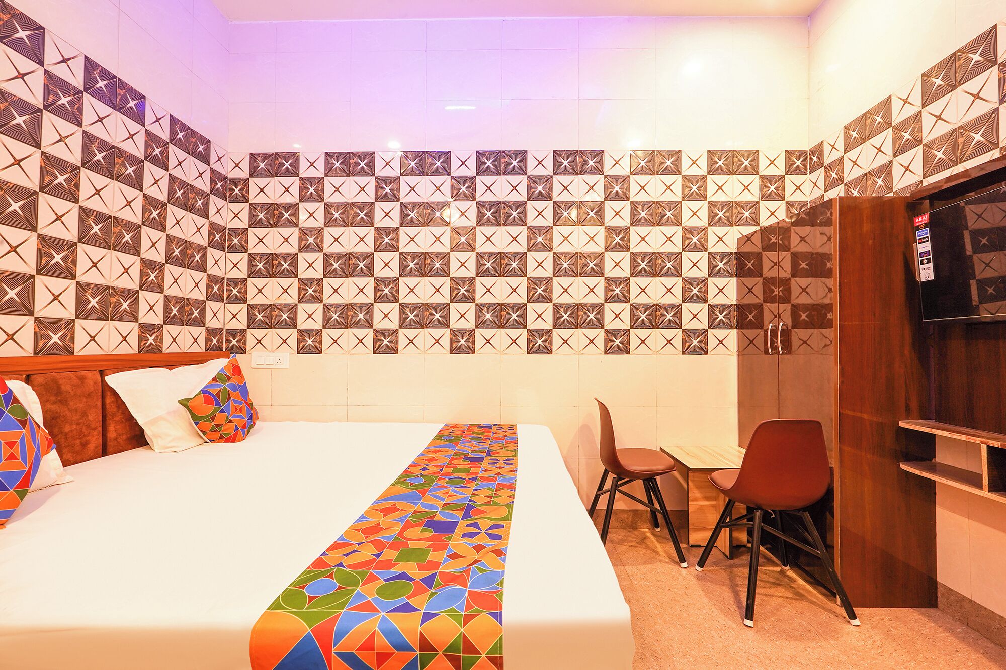 A hotel room with a bed, a desk, a chair, and a TV.