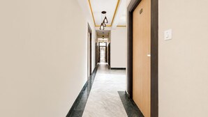 Een hotelgangen met een marmeren vloer, houten deuren en een plafond met geel accent.