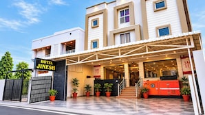 Een modern hotel met een opvallende ingang, een overdekte doorgang en een bord met 'Hotel Jinmesh'.