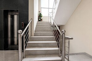 Un escalier avec des rampes et une main courante en métal, menant à un ascenseur.